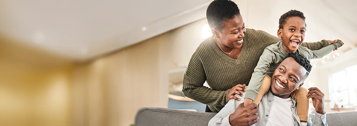 Two adults and a young child play together in a house.