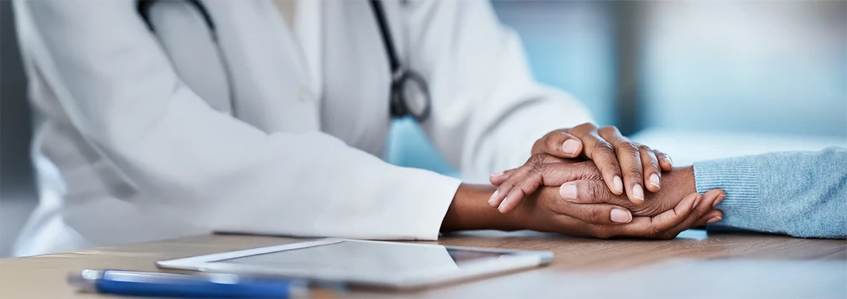 Two people hold hands on a table. The hands are the focal point.