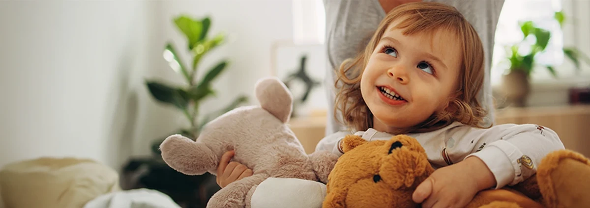 Small child smiling with teddy bear toys