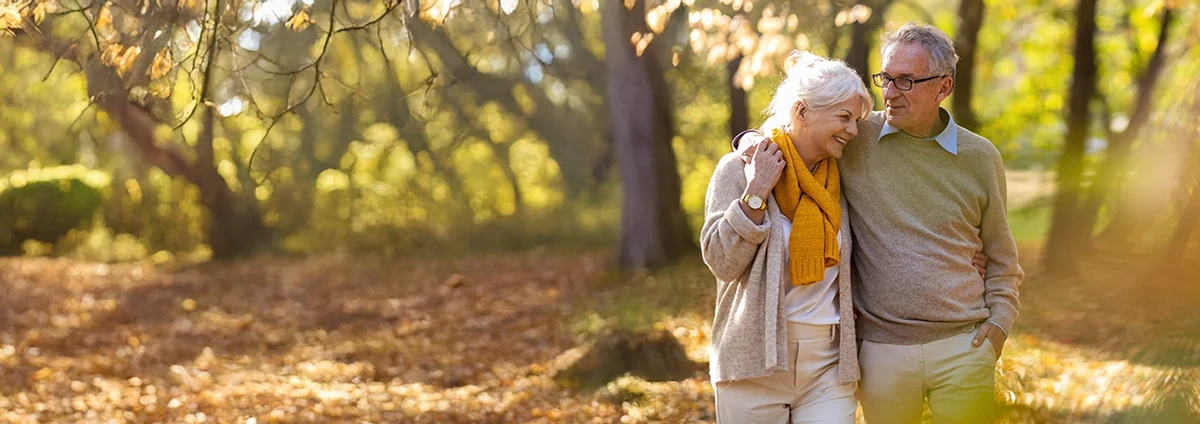 Smiling older couple walks in autumn woods 